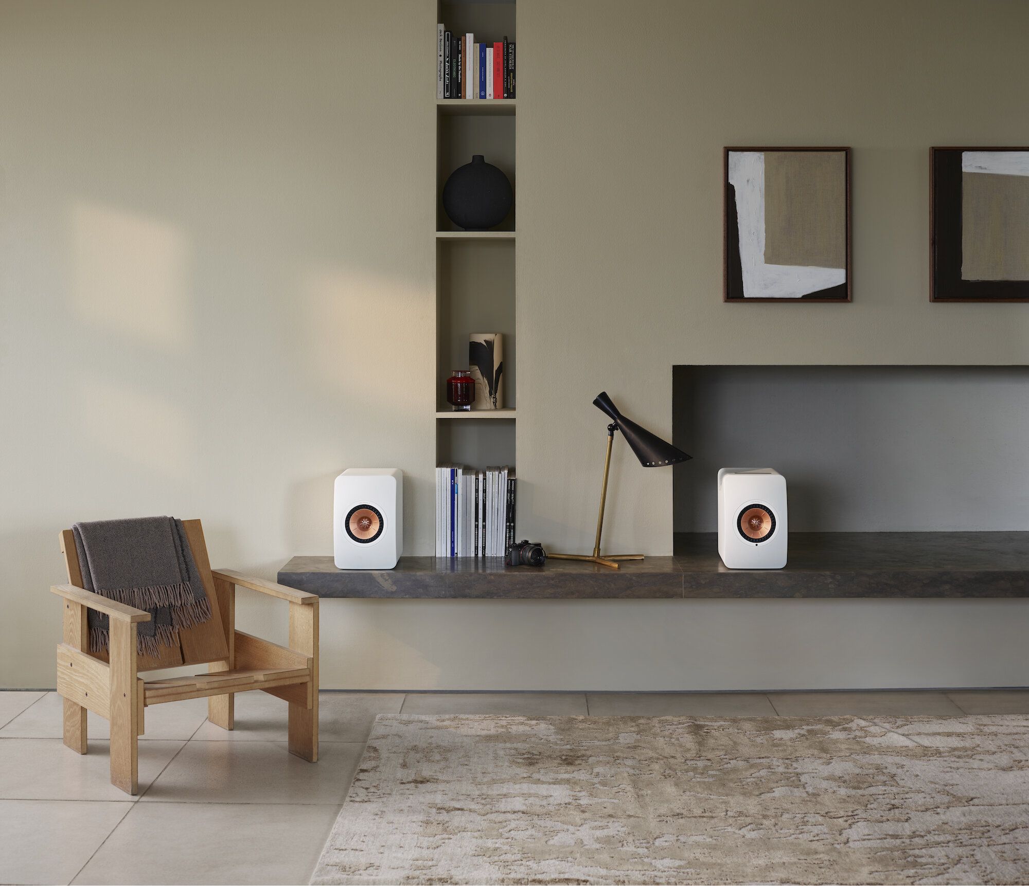 A modern living room with a KEF LS50 Wireless II speaker in Mineral White prominently placed among sleek furnishings and abundant natural light.